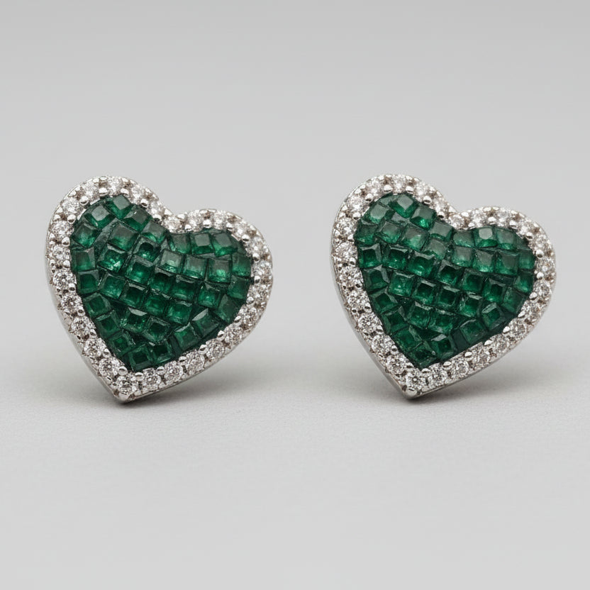 Heart-shaped earrings with green gemstones and clear stones on a light gray background