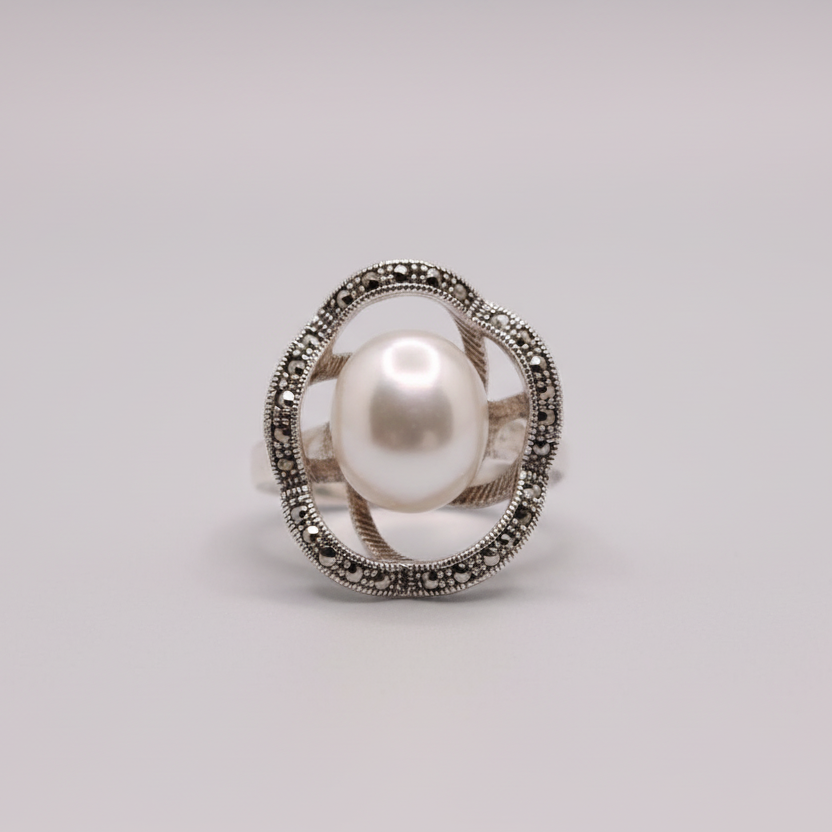 Silver ring with a pearl on a light blue fabric background