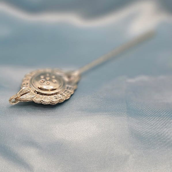 Decorative silver spoon on a textured blue fabric background