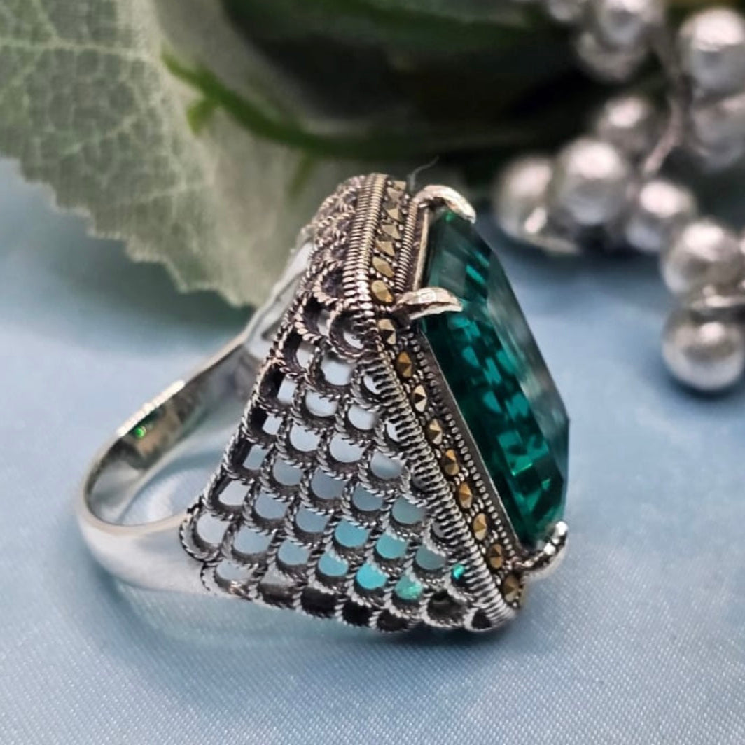 Silver ring with a green gemstone on a light blue background