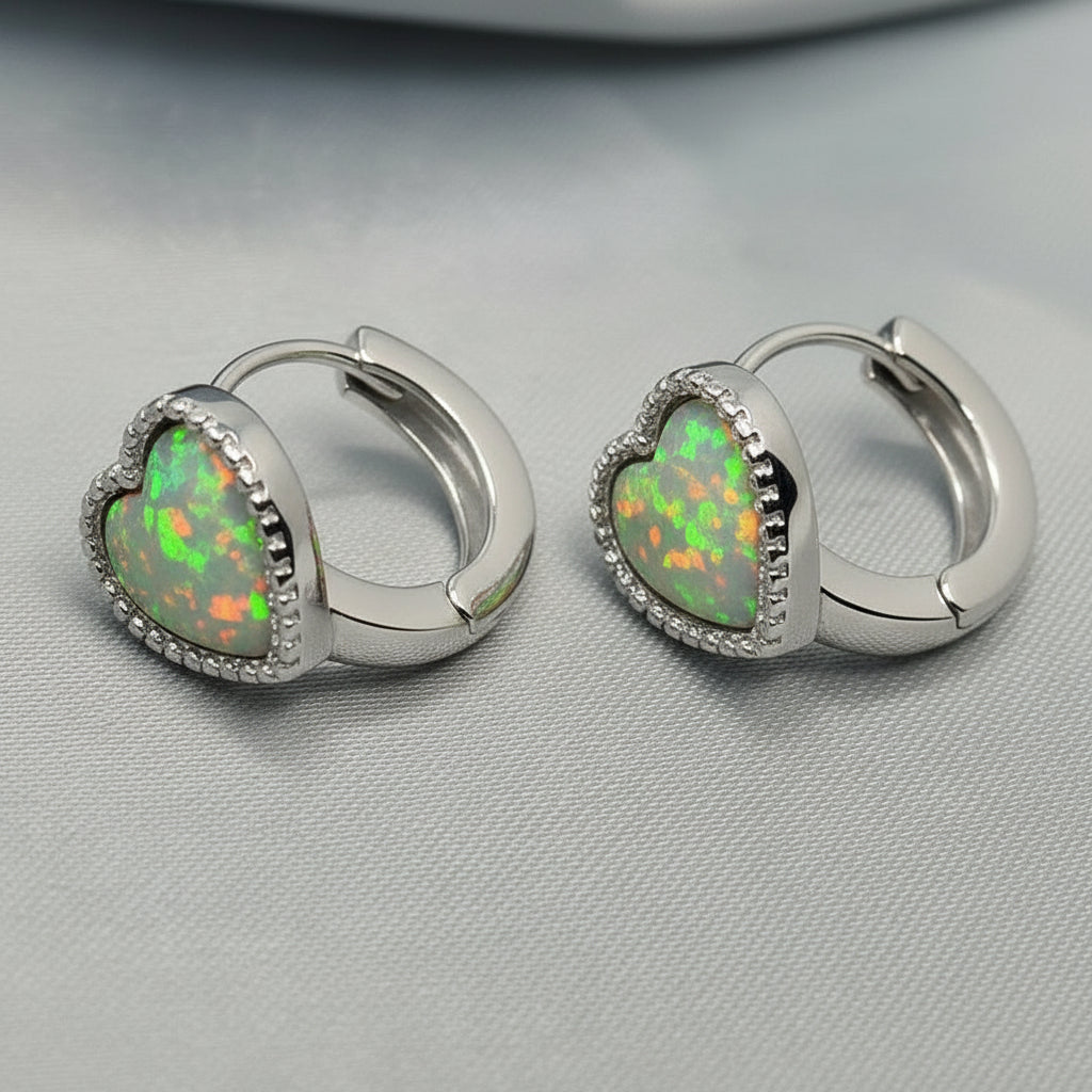 Pair of hoop earrings with heart-shaped opal stones on a gray background