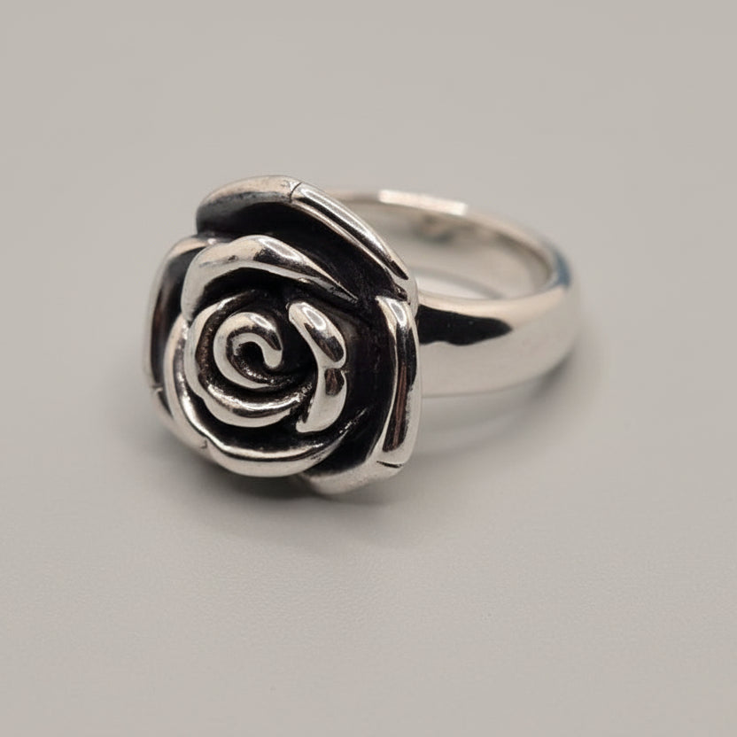 Silver rose-shaped ring on a light gray fabric background