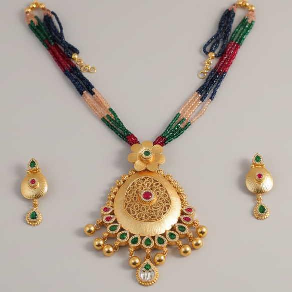 Gold necklace with green and red beads on a gray background