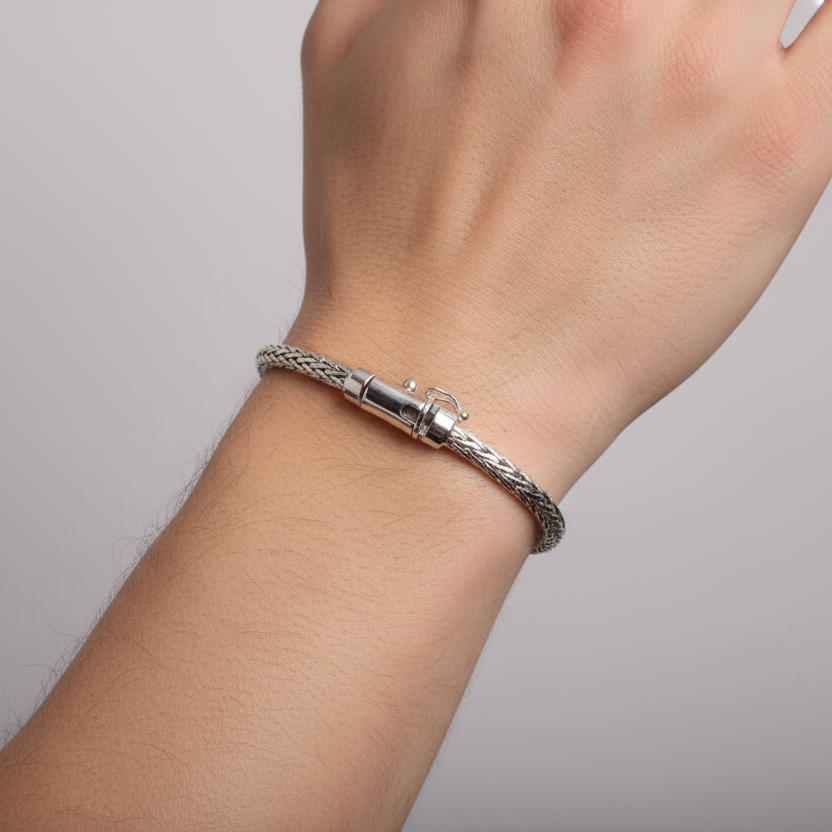 Silver braided bracelet with a clasp on a light gray background