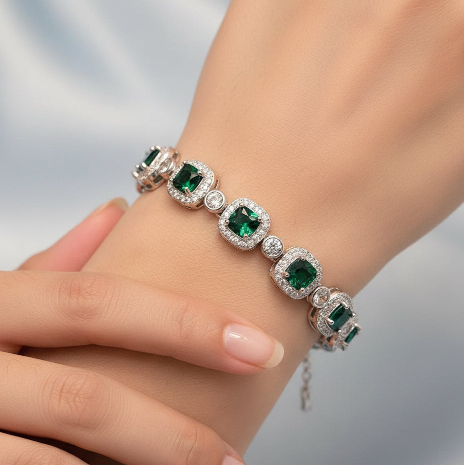 Silver bracelet with green gemstones on a light gray background