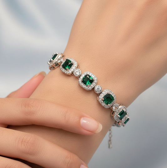 Silver bracelet with green gemstones on a light gray background