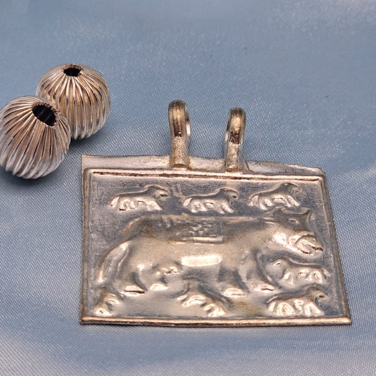 Silver pendant with a bear design on a blue fabric background