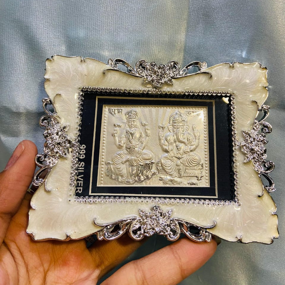 Decorative silver frame with a religious icon held by a hand against a light blue background
