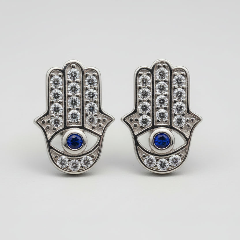 Pair of Hamsa hand earrings with gemstones on a light gray background