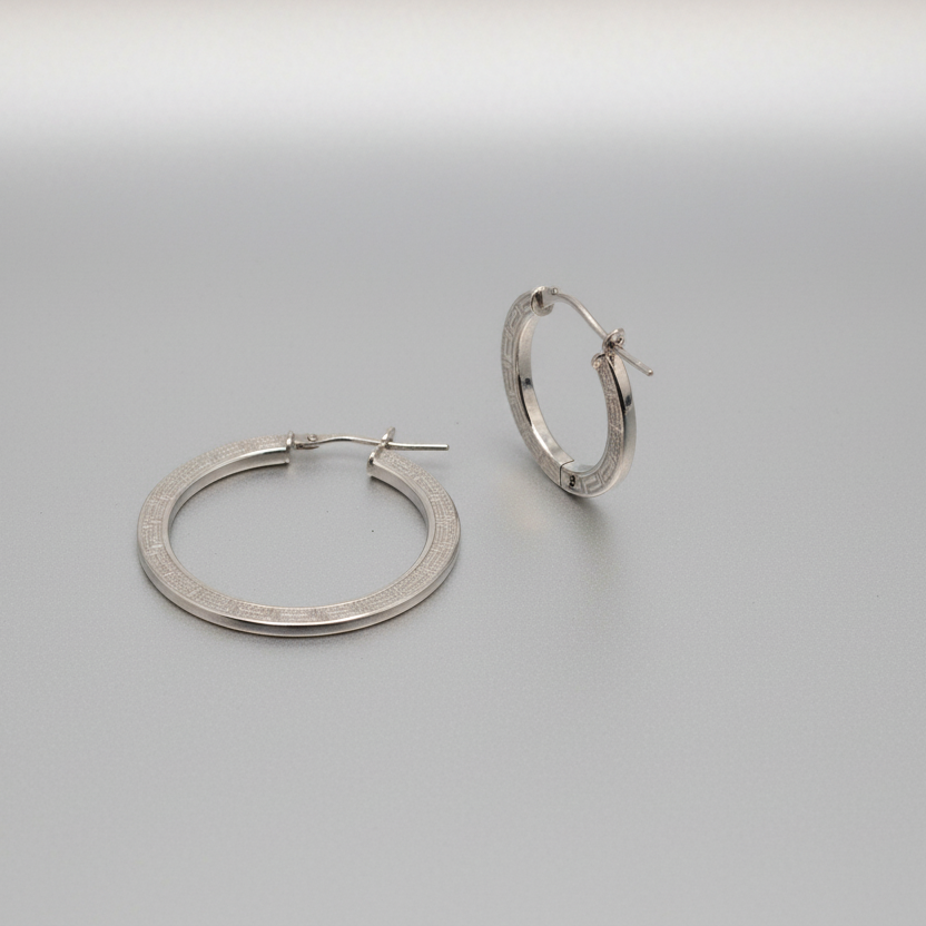 Pair of silver hoop earrings on a metallic surface