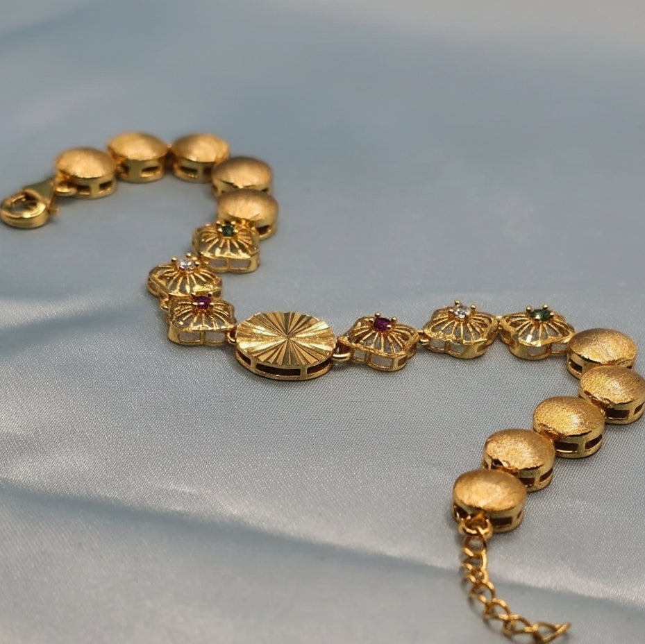 Gold bracelet with decorative elements on a light blue fabric background