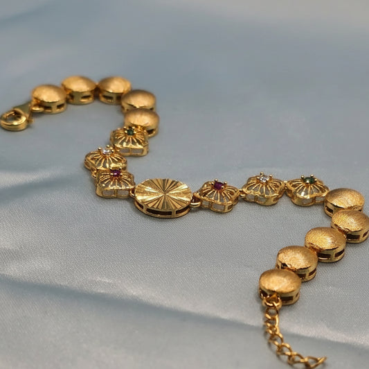 Gold bracelet with decorative elements on a light blue fabric background