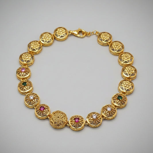 Gold bracelet with gemstones on a light gray background