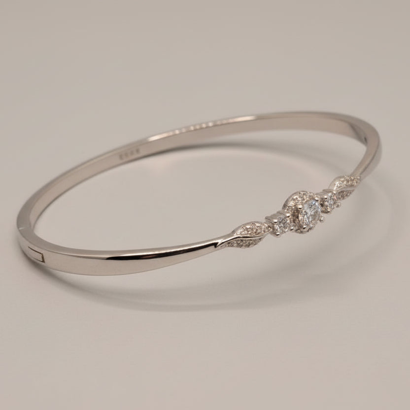 Silver bracelet with intricate design on a light blue fabric background