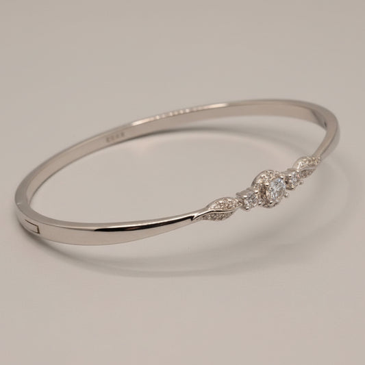 Silver bracelet with intricate design on a light blue fabric background