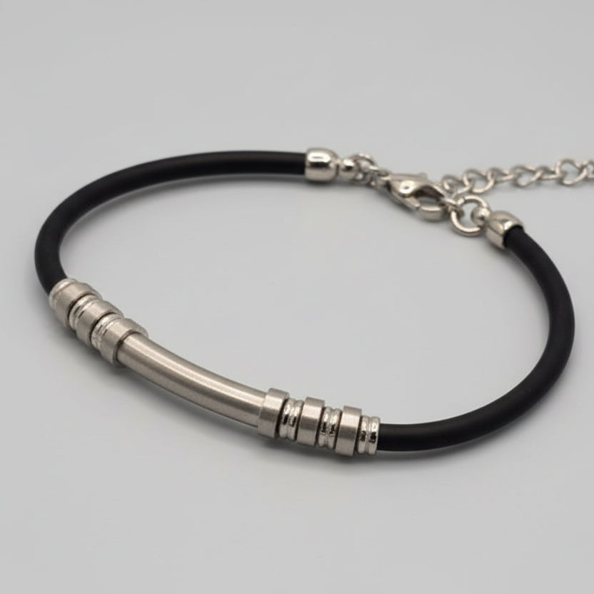 Silver bracelet with black cord on a light blue fabric background