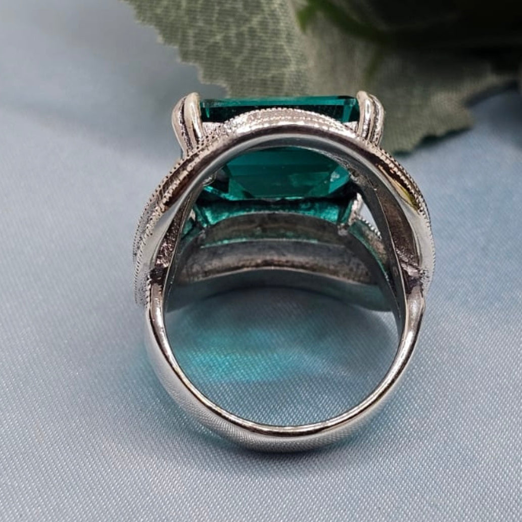 Silver ring with a green gemstone on a light blue fabric background