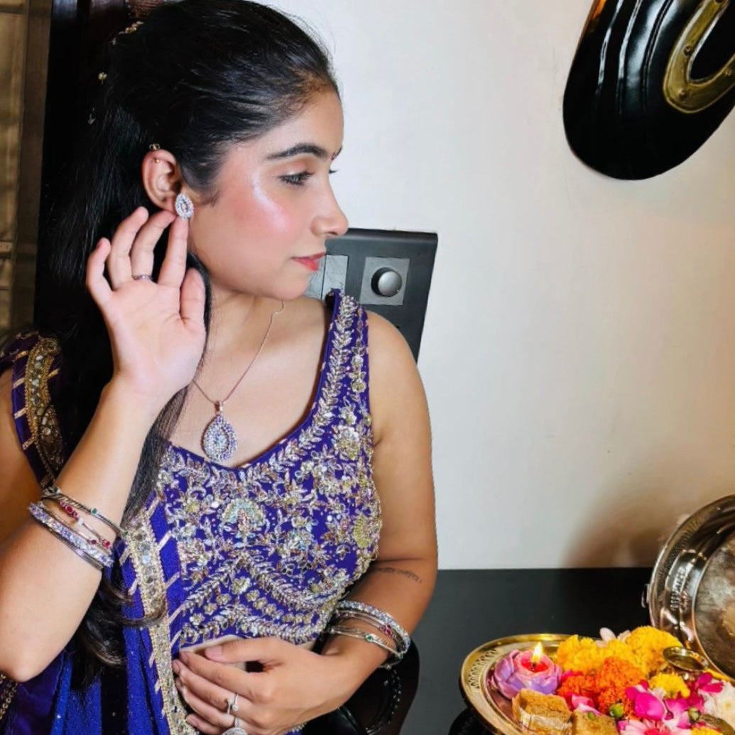Woman adjusting an earring in front of a mirror with decorative items on a table.