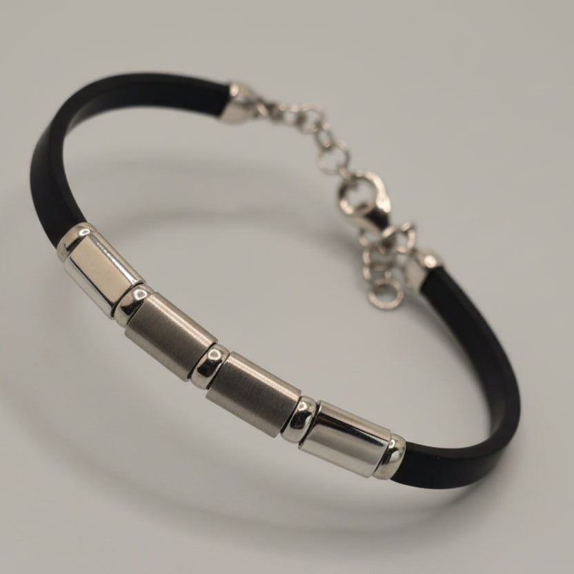 Silver bracelet with black strap on a light blue fabric background