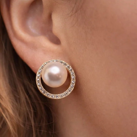 Pearl earring with rose gold circle and clear stones worn on an ear