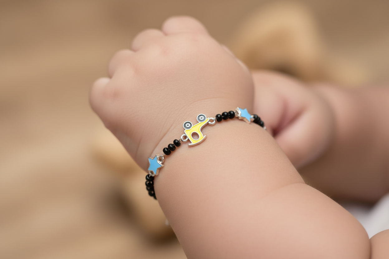 Black beaded necklace with colorful charms on a light gray surface, next to a beige fabric ball.