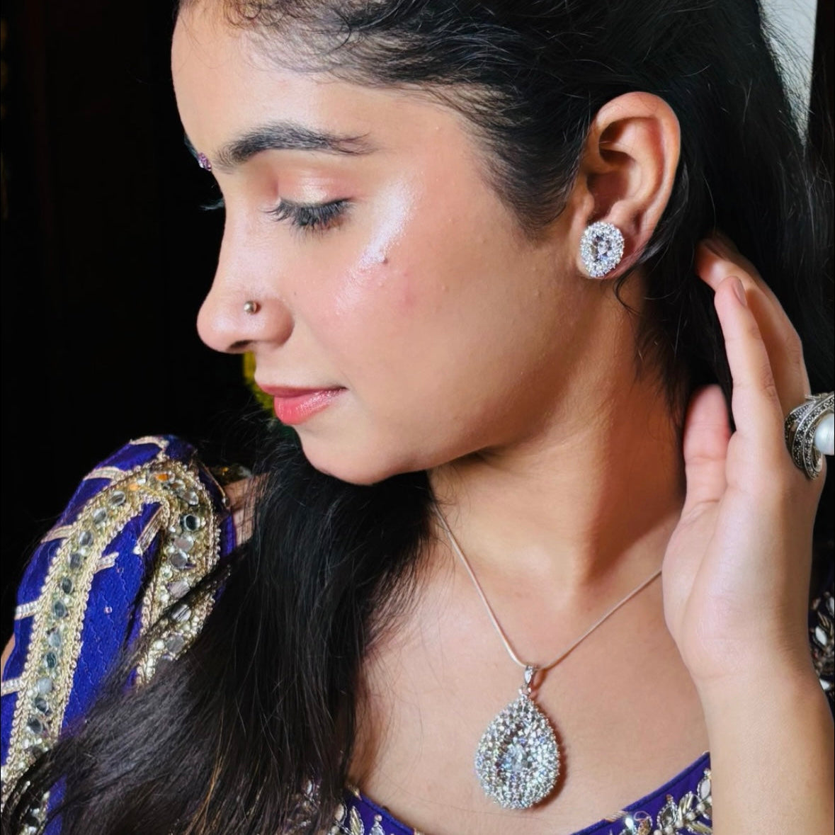 Woman wearing jewelry, including earrings and a necklace, with a blurred background.
