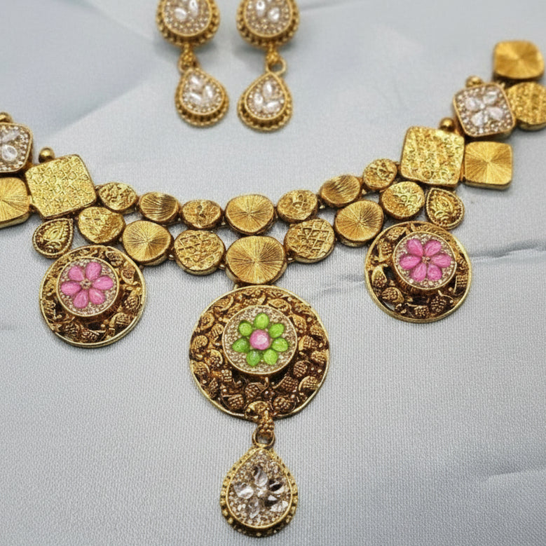 Gold necklace with floral and green stone pendants on a light gray background