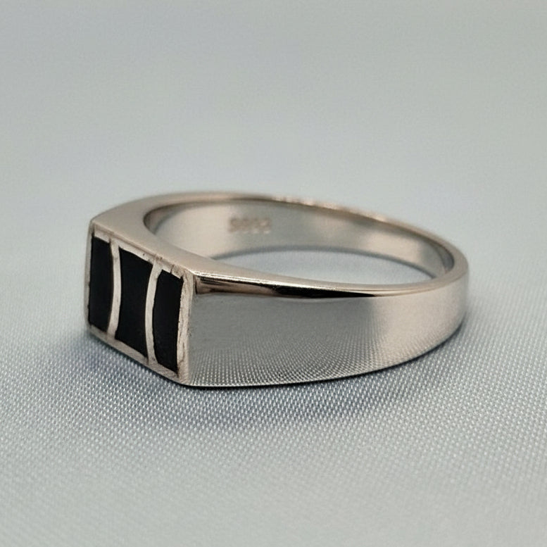 Silver ring with a geometric design on a gray fabric background