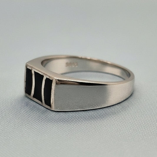 Silver ring with a geometric design on a gray fabric background