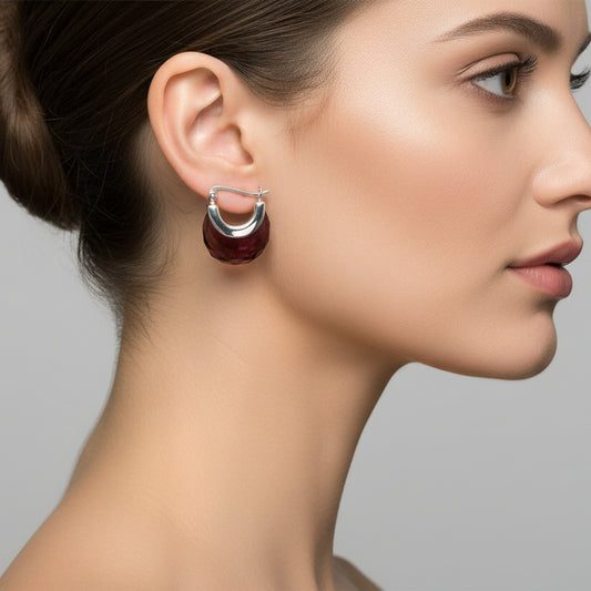 Pair of earrings with brown faceted stones and silver loops on a light gray background