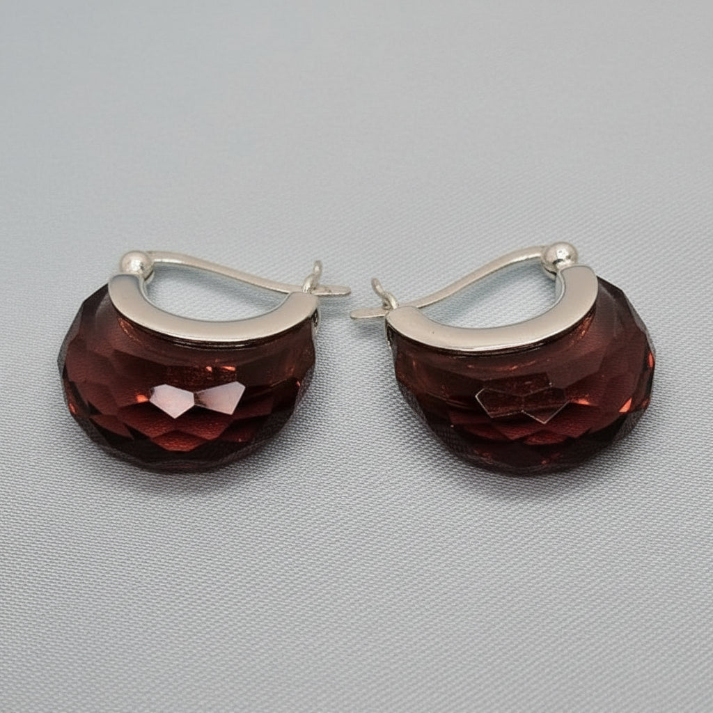 Pair of earrings with brown textured design and silver hoop on a gray background