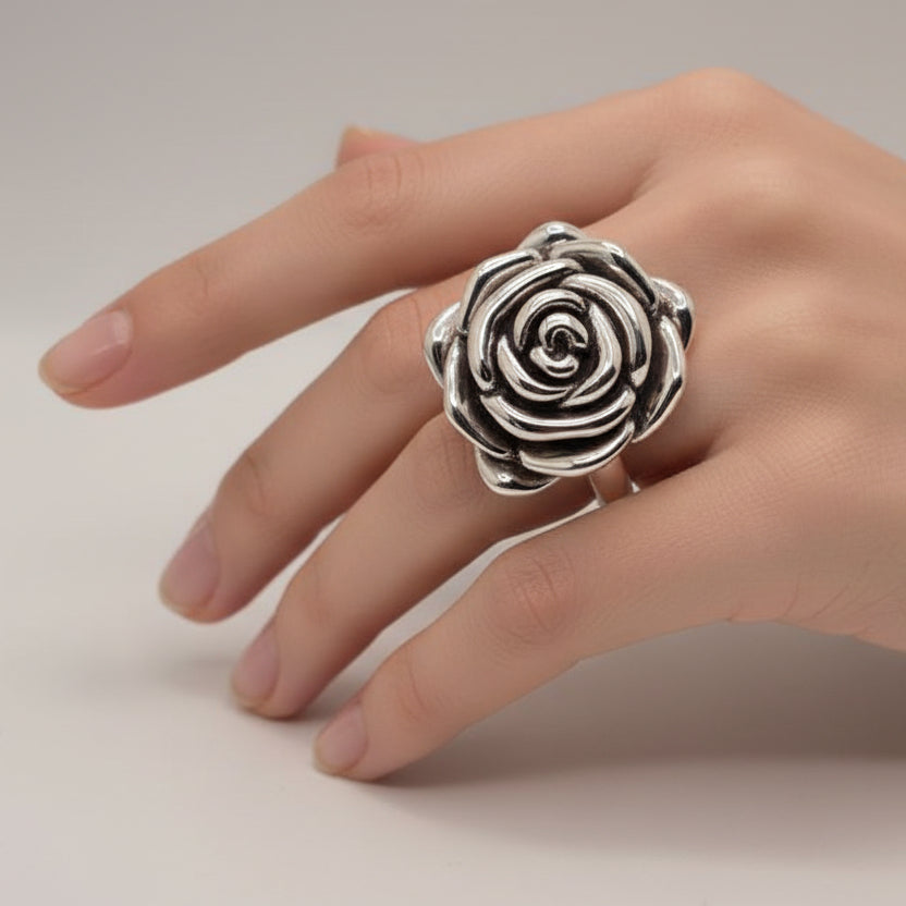 Silver rose-shaped ring on a light blue fabric background