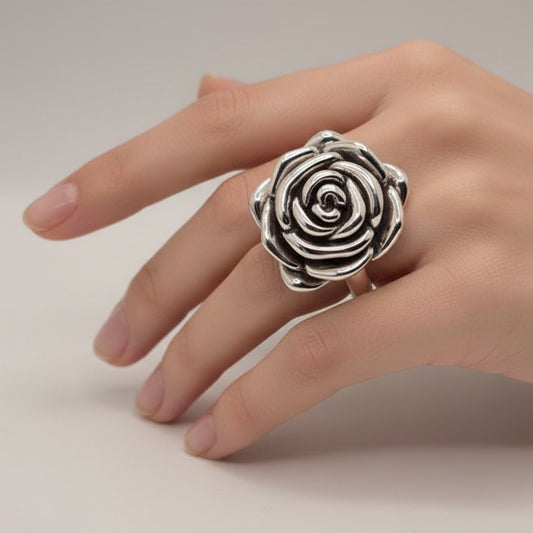 Silver rose-shaped ring on a light blue fabric background