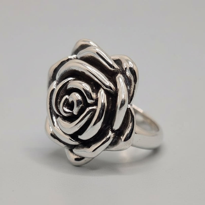 Silver rose-shaped ring on a light blue fabric background