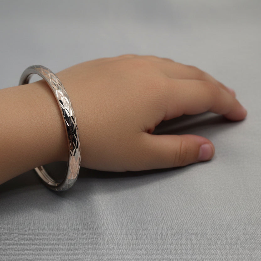 Silver bangle with textured design on a gray fabric background