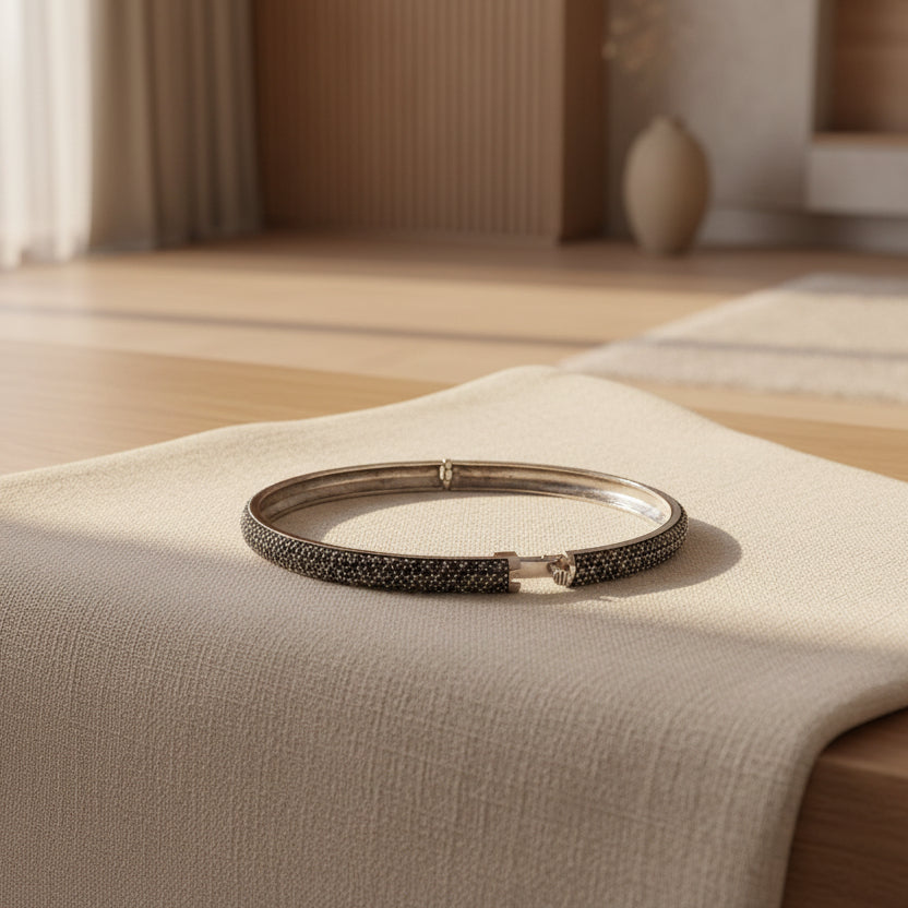 Silver bracelet with black stones on a light gray surface