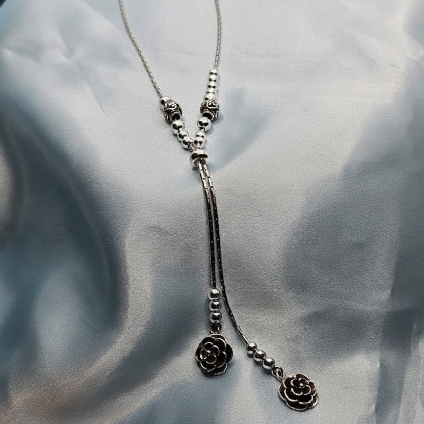 Silver necklace with floral pendants on a light gray fabric background