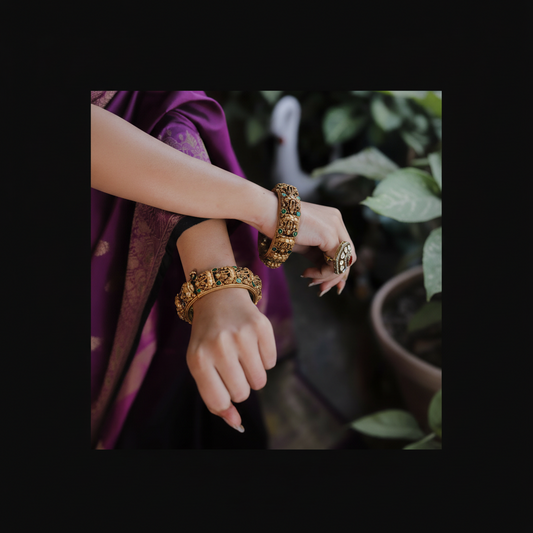 Close-up of hands wearing gold bangles with a blurred natural background