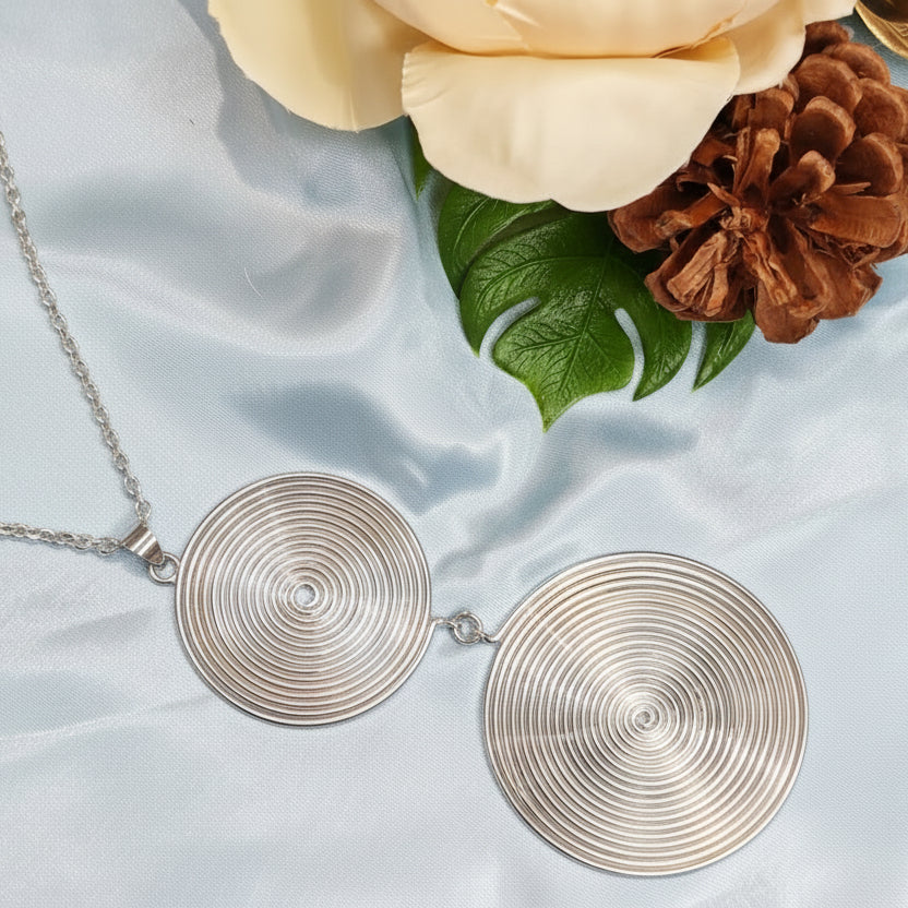 Necklace with circular pendants on a light fabric background with flowers and pinecones.